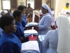Mhudumu Mkuu wa Shirika la Dada Wadogo, Jimbo Kuu Katoliki la Dar es Salaam, Sista Doreen Mwakaliku, akiwakabidhi  nguo baada ya kupandishwa hadhi ya utawa Wapostulanti na kuwa Wanovisi katika Shirika hilo.